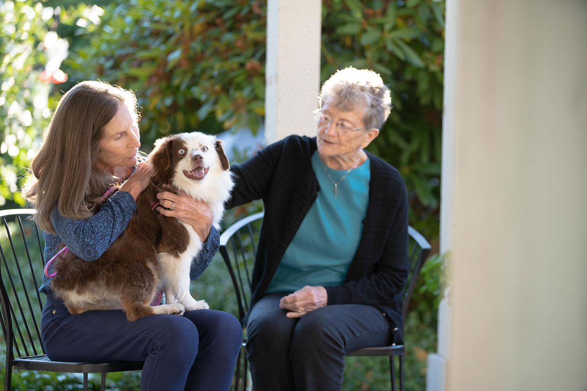 mother and daughter petting their dog